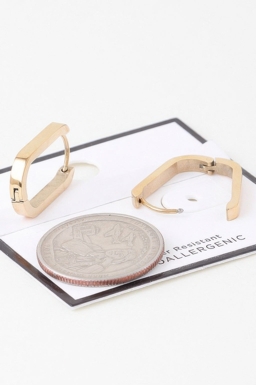 Gold-tone oval link hoop earrings with hinged oval frame and visible coin size