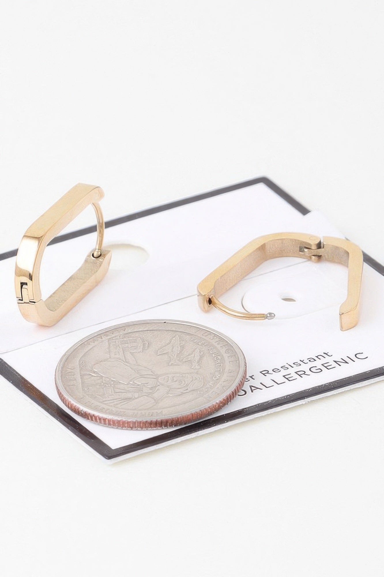 Gold-tone oval link hoop earrings with hinged oval frame and visible coin size