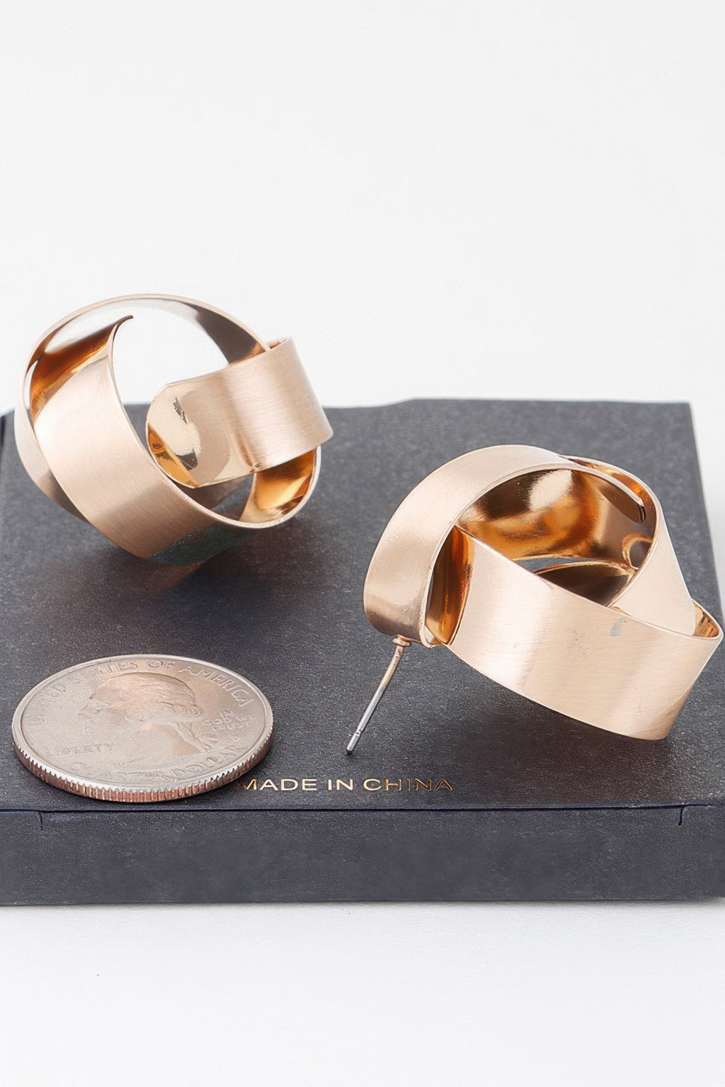 Gold curved hoop earrings, flat post backs visible, polished shiny finish