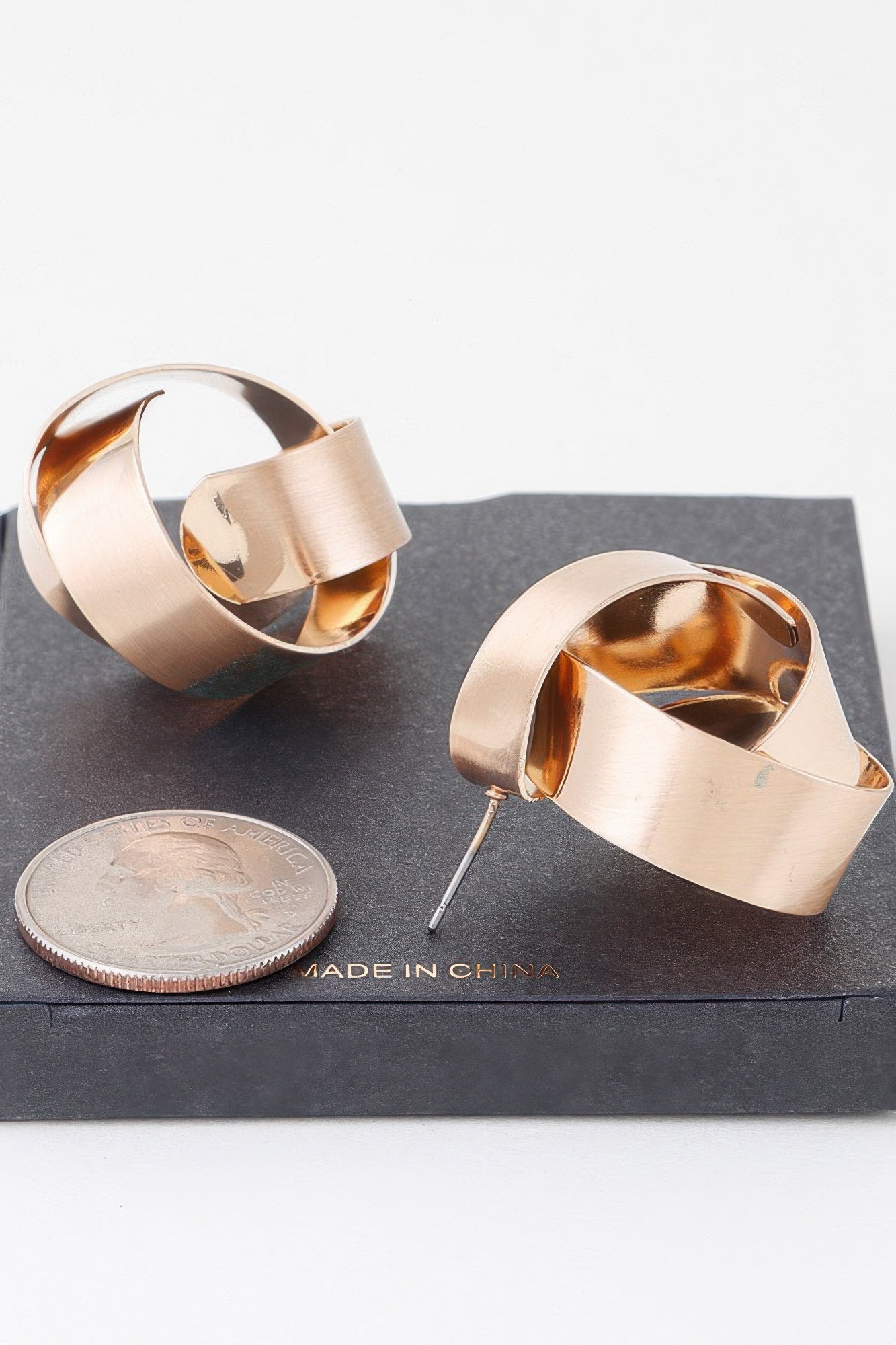 Gold curved hoop earrings, flat post backs visible, polished shiny finish