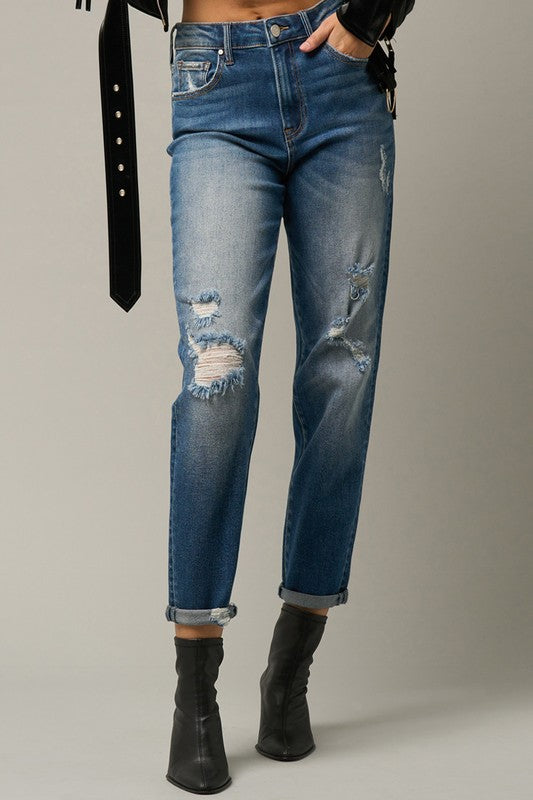 Dark blue distressed girlfriend jeans with ripped knees and frayed cuffed hem.
