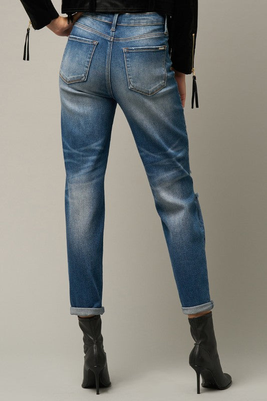 Back view of dark blue distressed girlfriend jeans with pockets and faded wash.