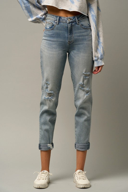 Medium wash distressed girlfriend jeans with ripped knees and cuffed hem