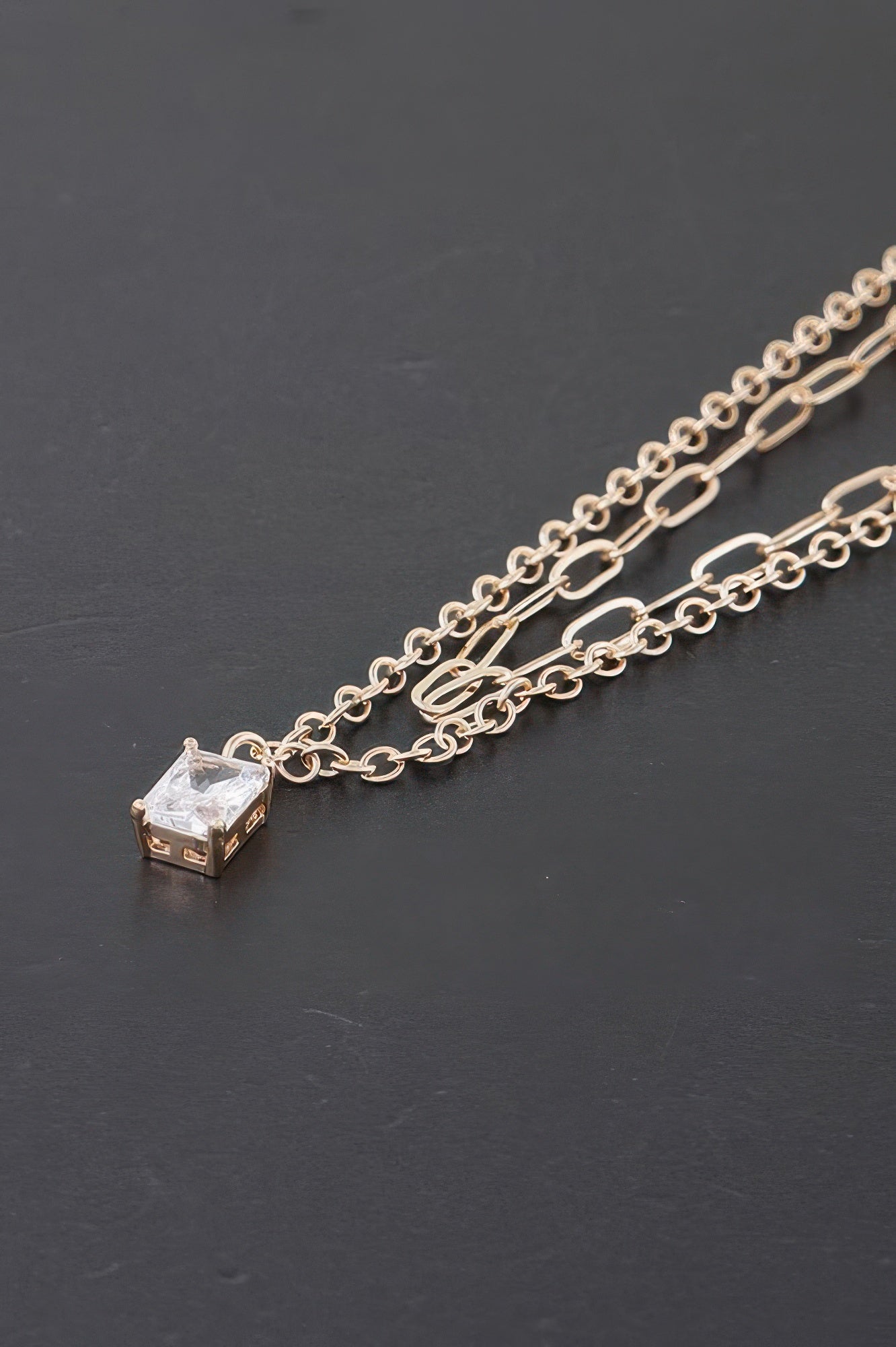 Close view of gold double chain necklace with clear cubic crystal square pendant