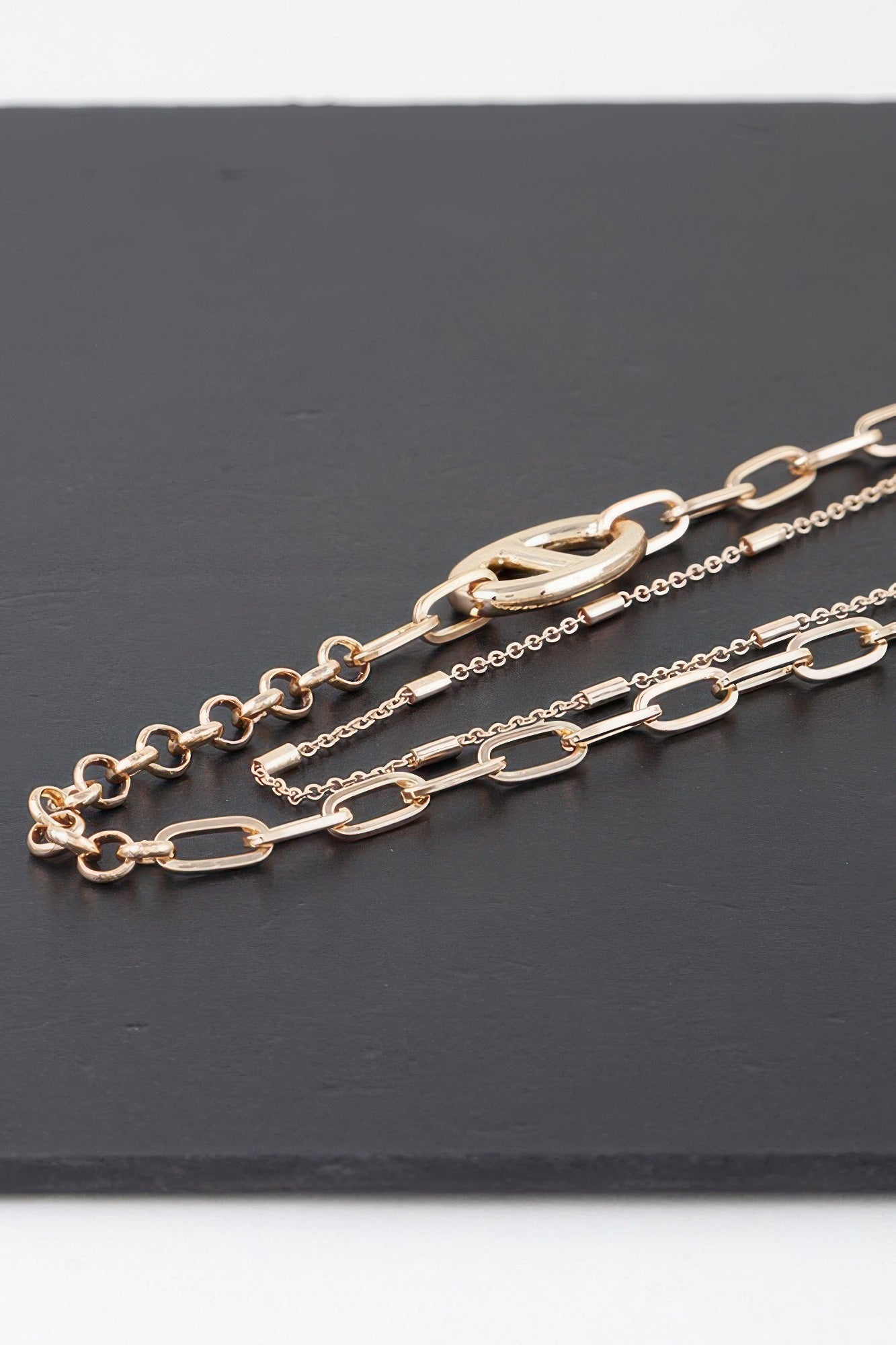 Gold double-link choker necklace close-up with oval links and circular charm
