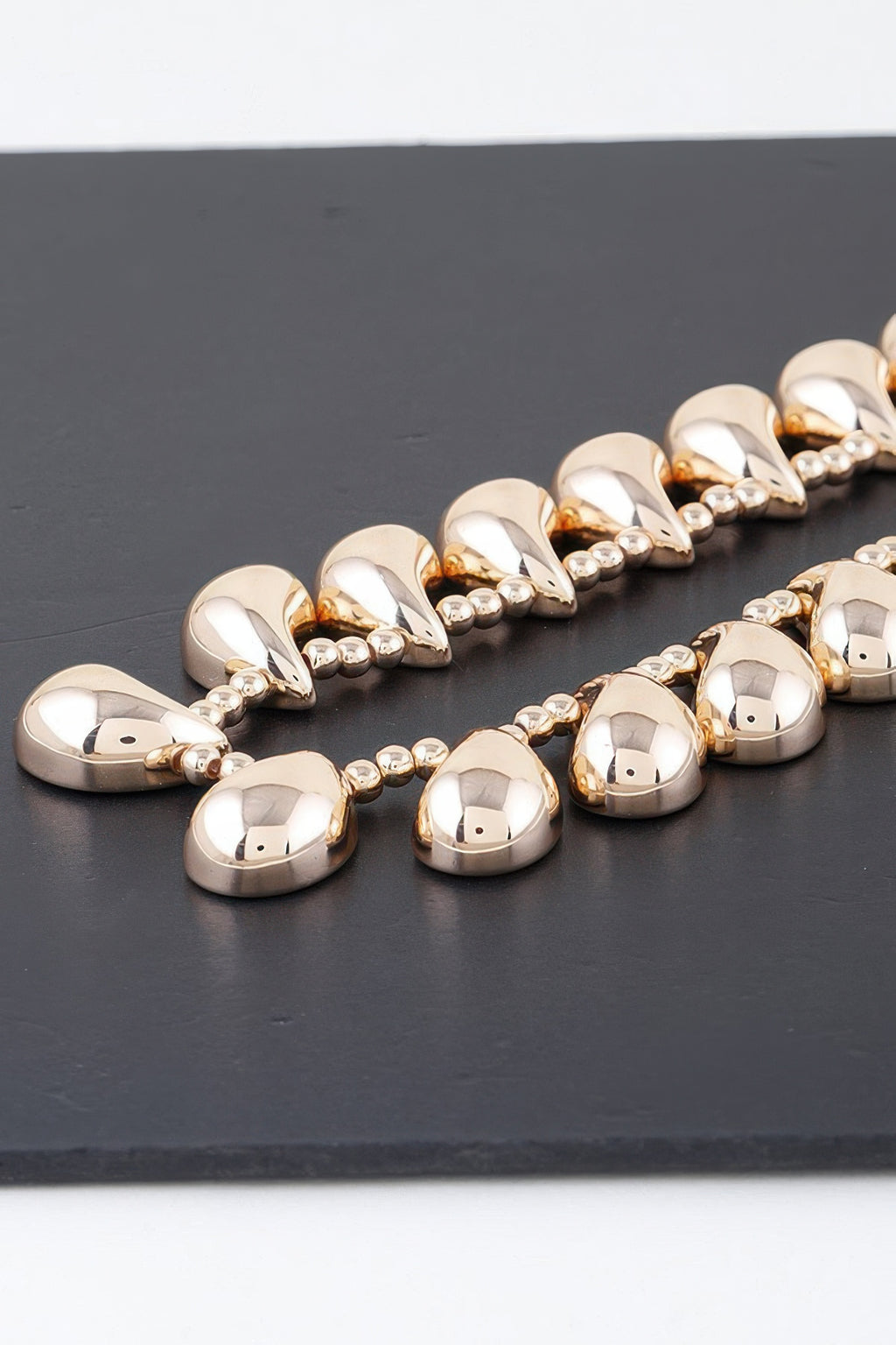 Close-up gold double-link choker links with polished teardrop faces