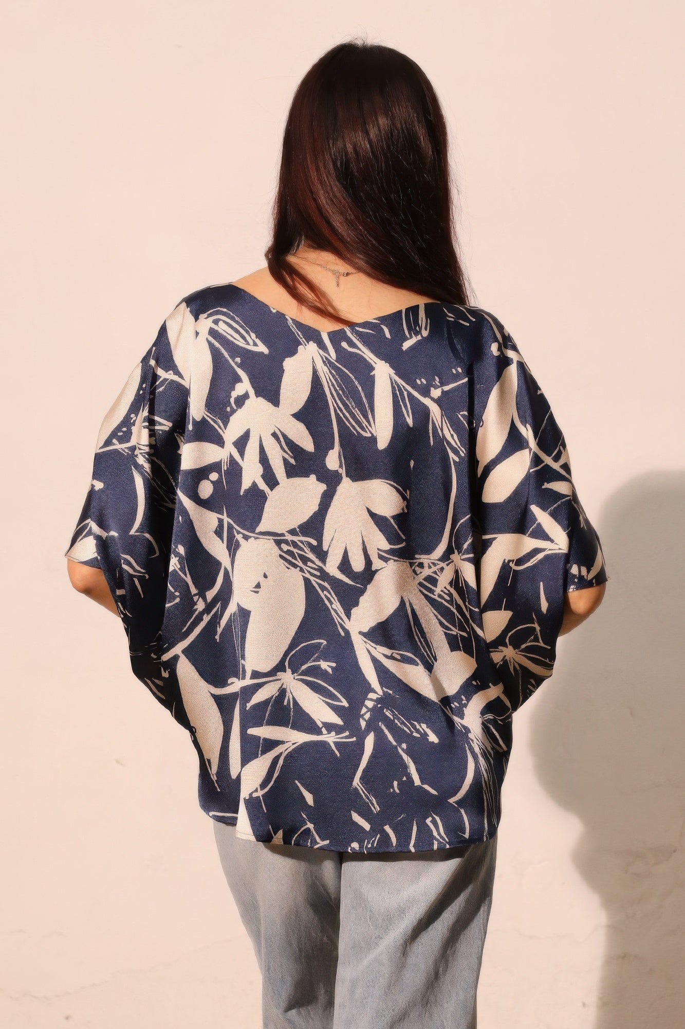Navy satin dolman drawstring top, back view with floral print and draped fit.