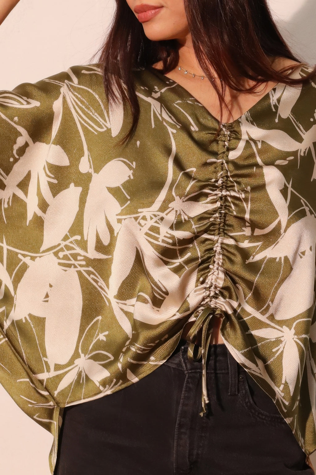 Olive satin dolman top close-up: V-neck with gathered drawstring ruching and floral print.