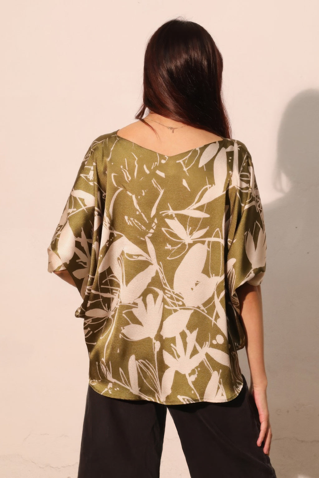 Olive satin dolman drawstring top, back view with floral print and loose drape sleeves.