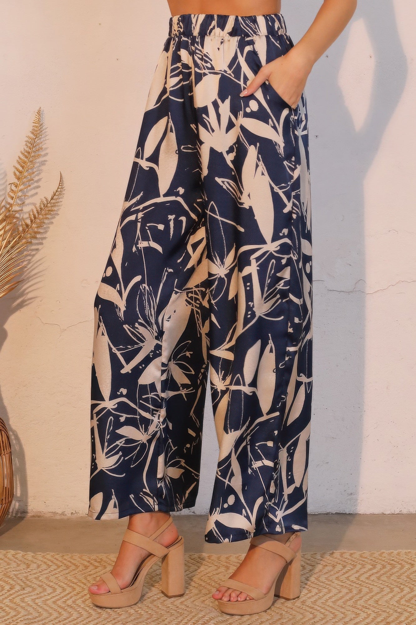 Navy satin pants with cream botanical print, loose wide-leg silhouette, side view