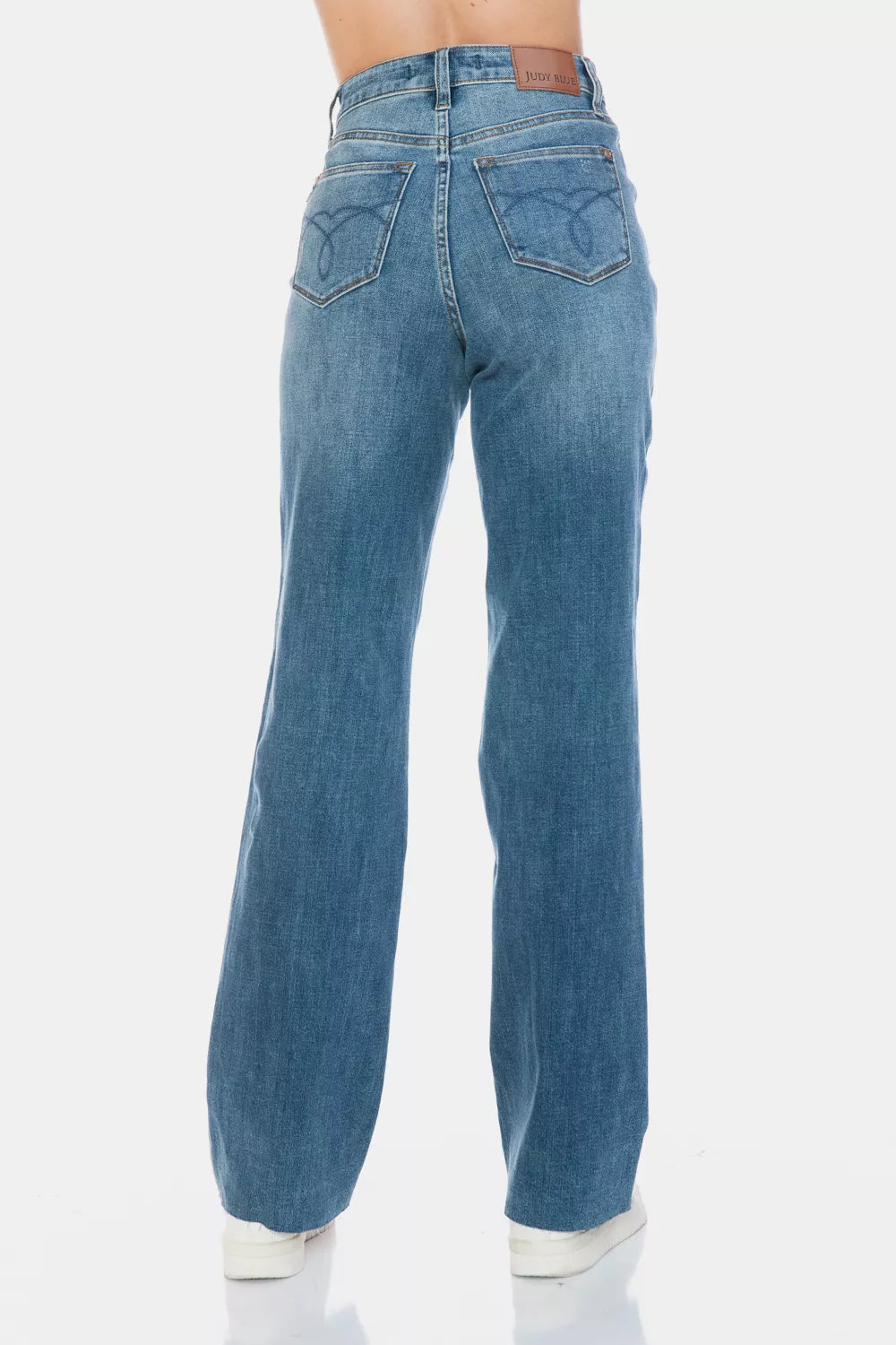 Medium-wash straight jeans from back view with rear pockets and raw hem