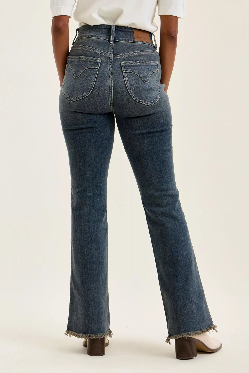 Back view of medium-wash high-waist jeans with two pockets and frayed hem