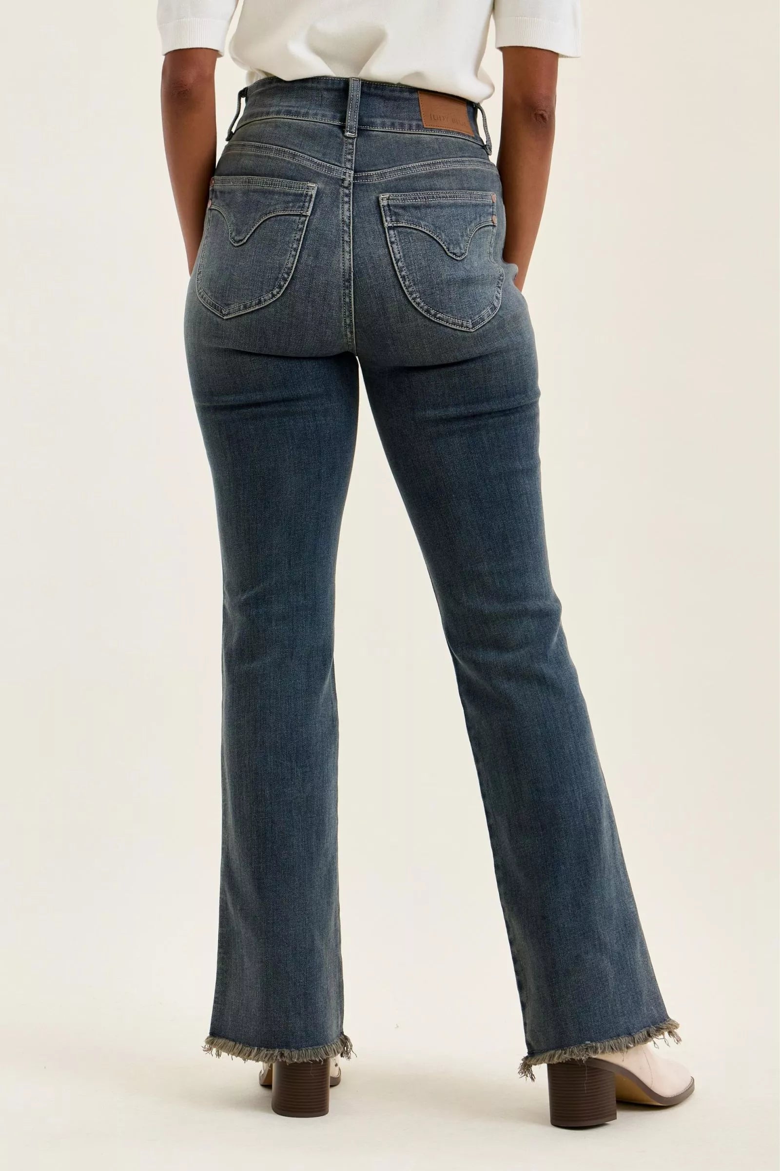 Back view of medium-wash high-waist jeans with two pockets and frayed hem