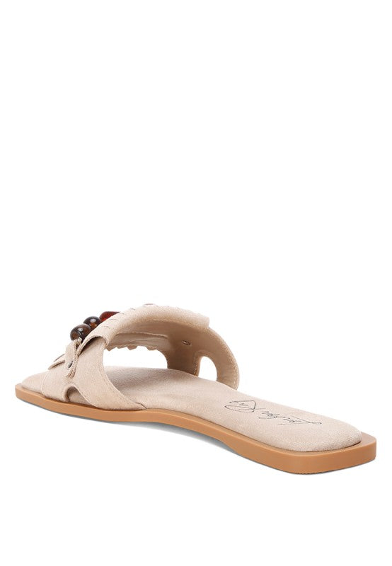 Beige microfiber slide sandal, side view with bead cluster and fringe trim on strap