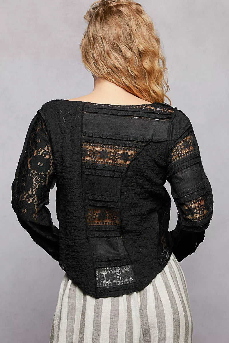Back view: black round-neck long-sleeve top with exposed seams and lace panels