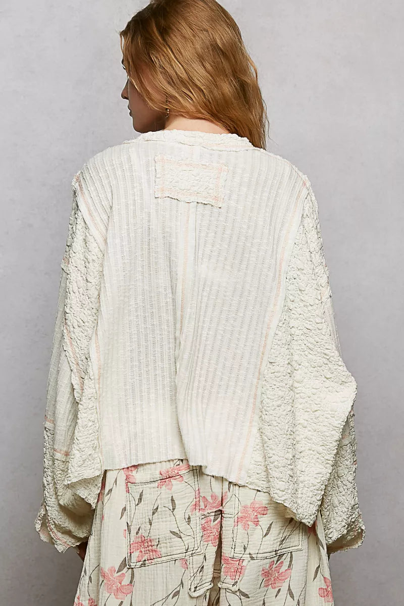 Back view: off-white V-neck long-sleeve top with stitched panels