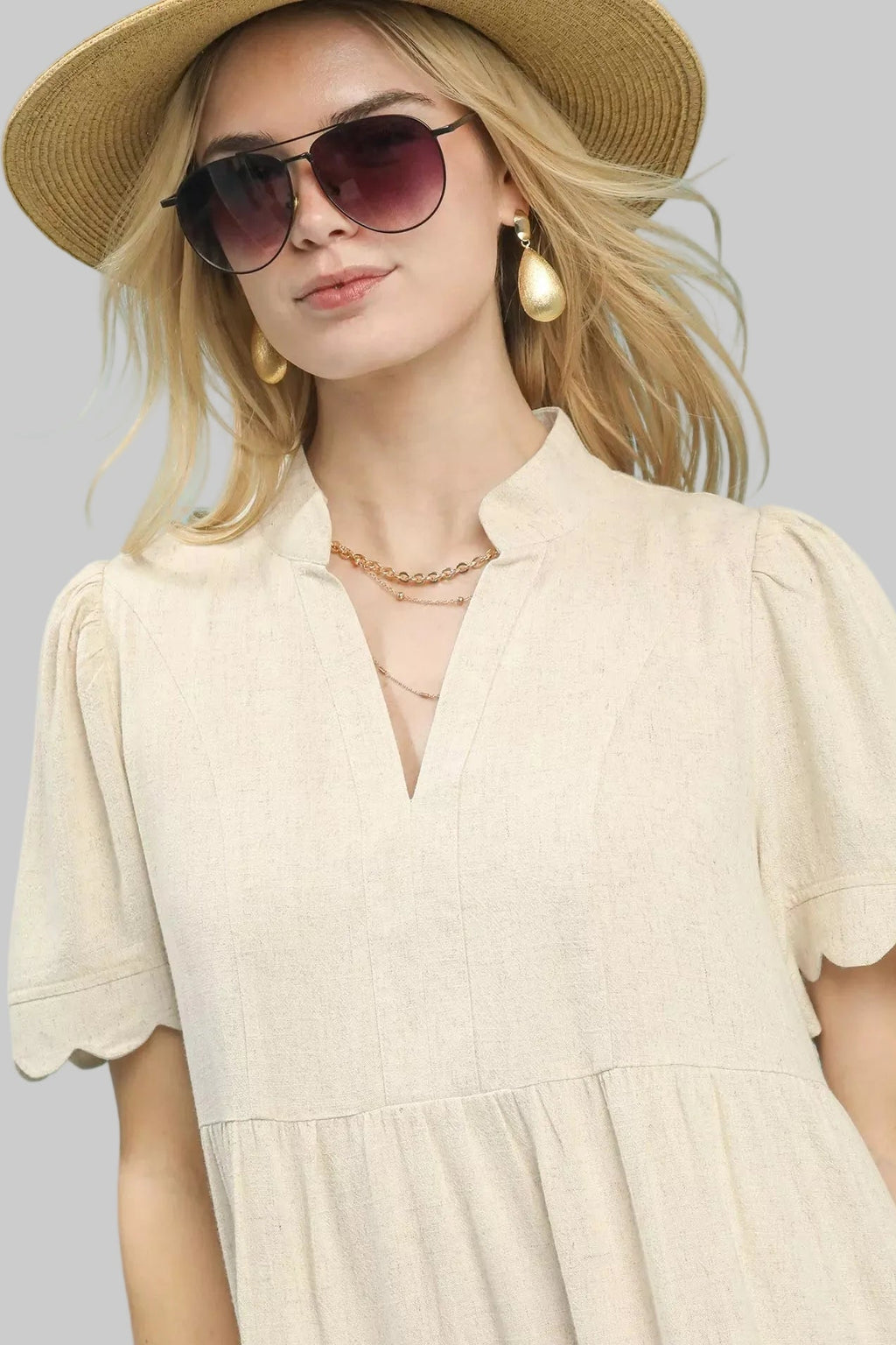 Close-up neckline: oatmeal linen babydoll dress with V-neck and scalloped sleeves
