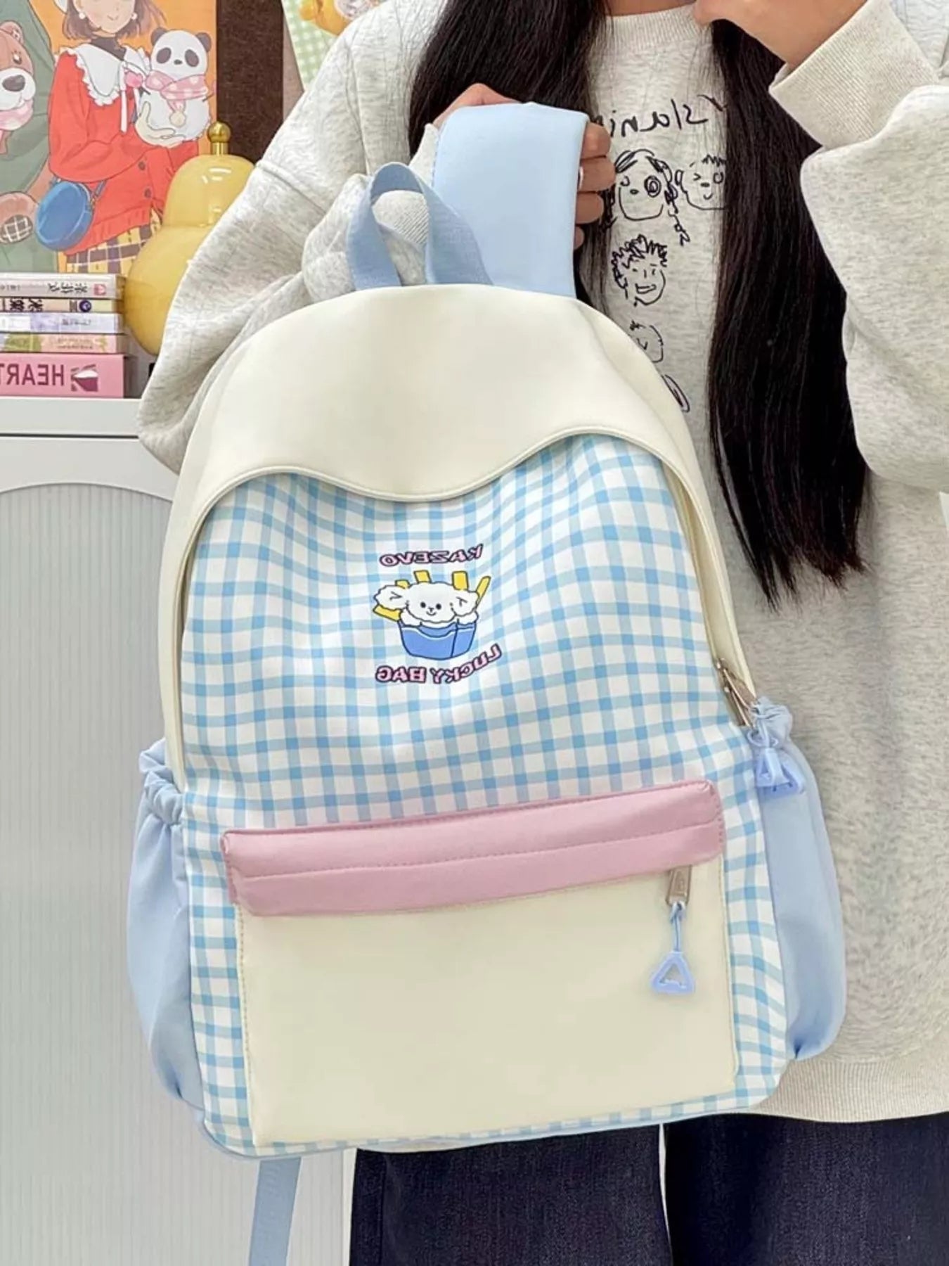 Blue gingham backpack with cartoon patch, pink zip pouch, cream top flap and straps.