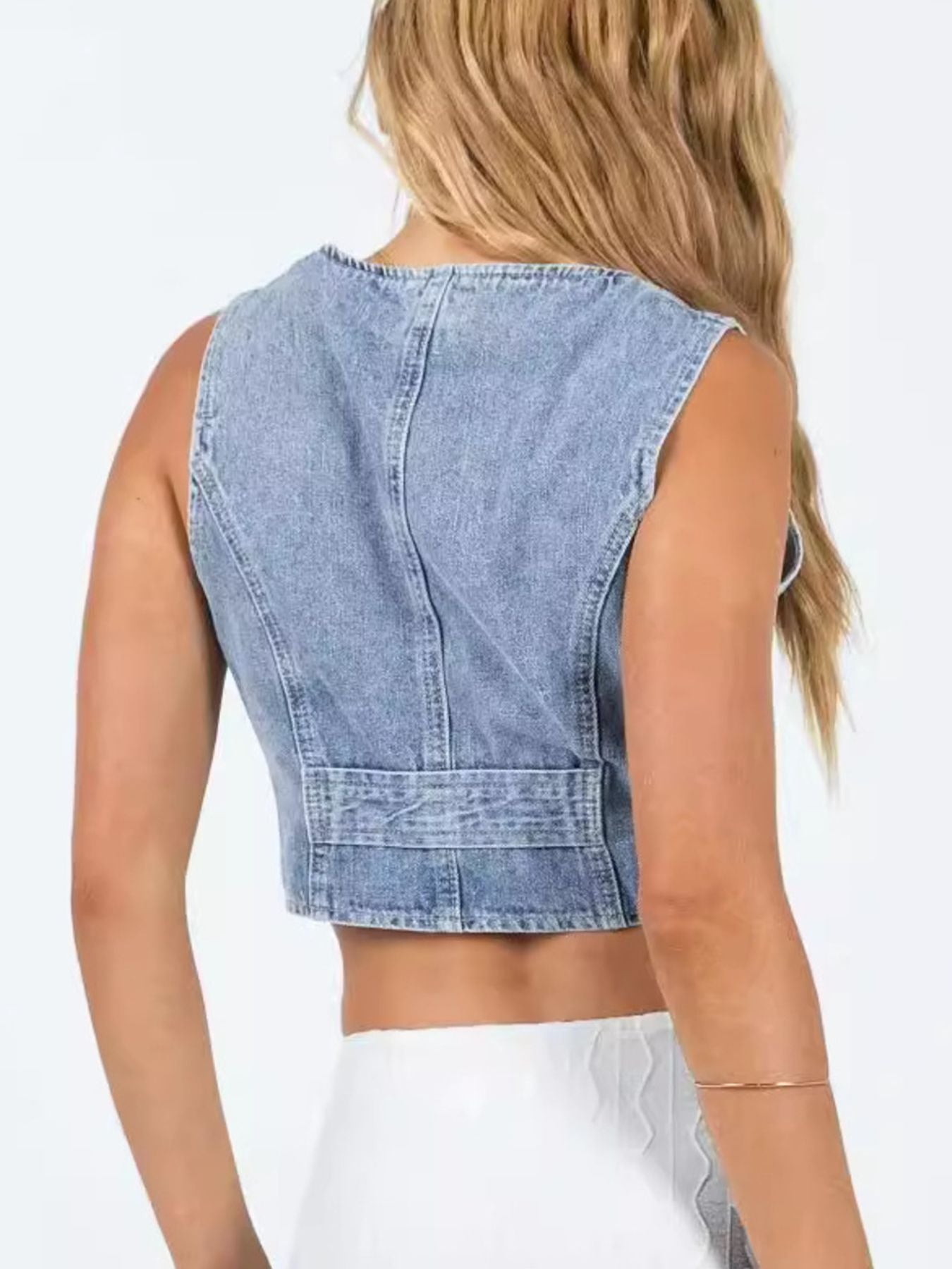 Back view of light-wash denim sleeveless vest with yoke seam and waistband