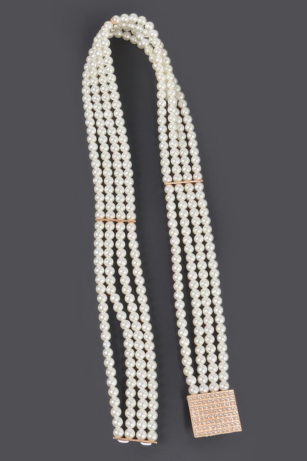 Ivory pearl elastic belt laid out, with square rose-gold buckle and hanging ends