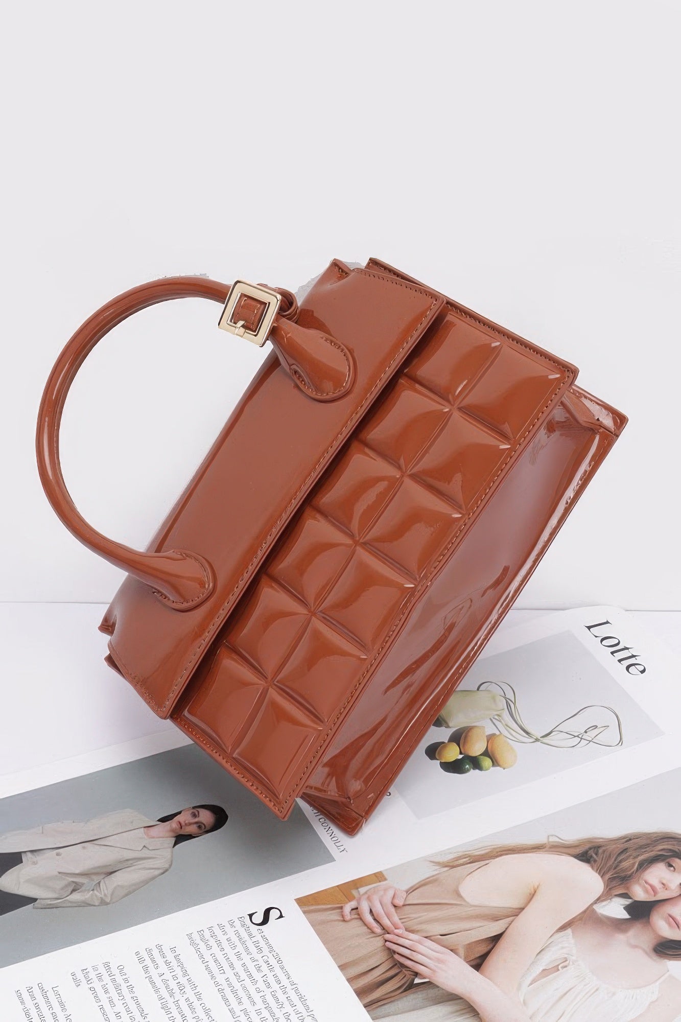 Camel embossed enamel top handle bag, side view of flap and textured front panel