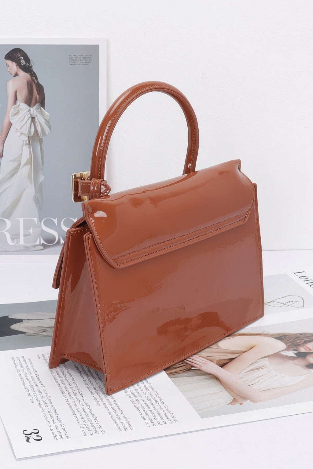 Camel embossed enamel top handle bag, front angle with glossy finish and buckle