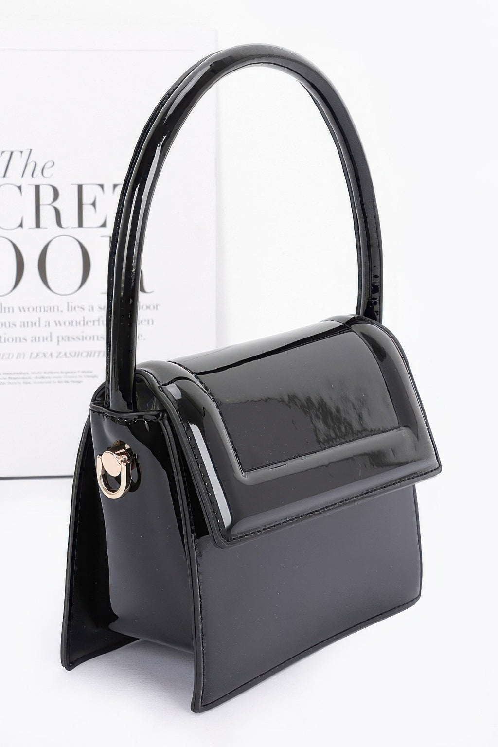 Enamel top handle flap bag, black side view with curved handle and chain strap