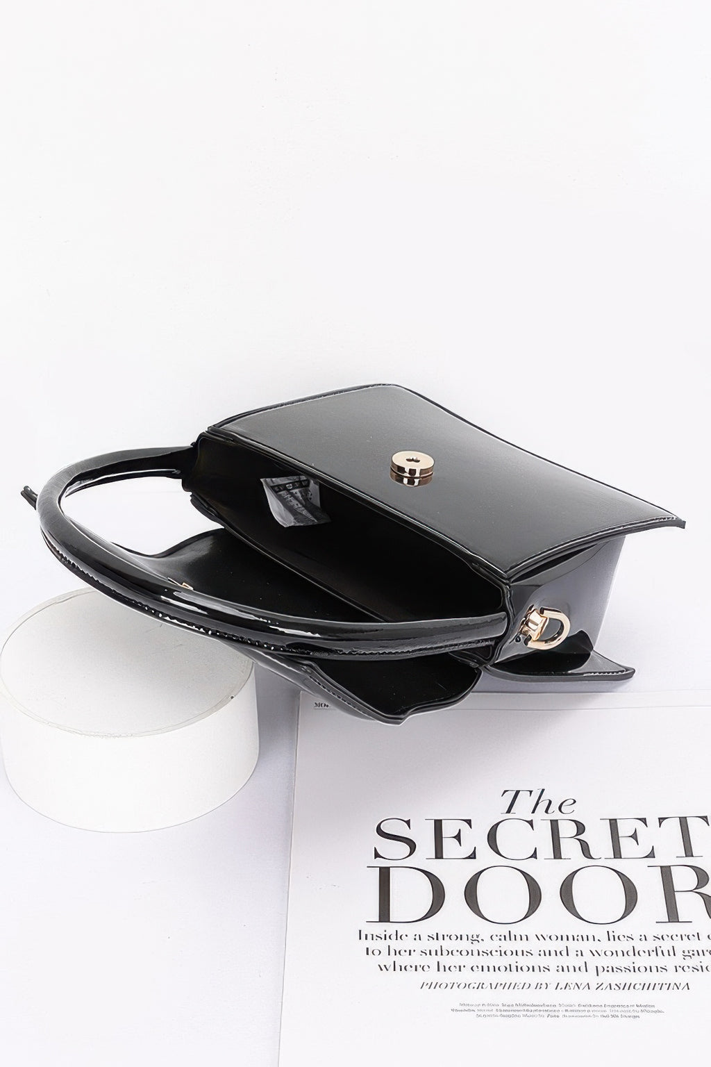 Enamel top handle flap bag, black with open interior and top clasp detail