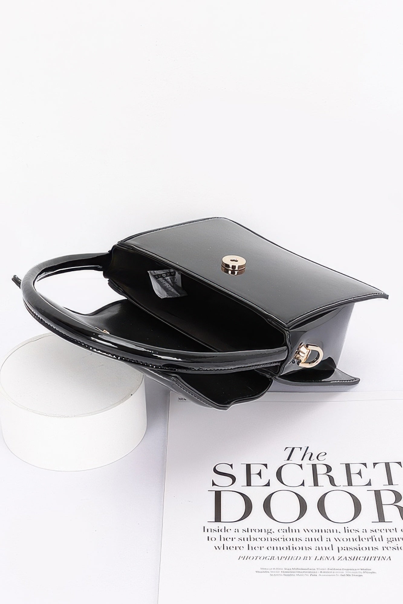 Enamel top handle flap bag, black with open interior and top clasp detail