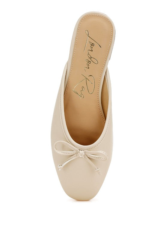 Beige slip-on flat mule with bow at toe; interior lining visible