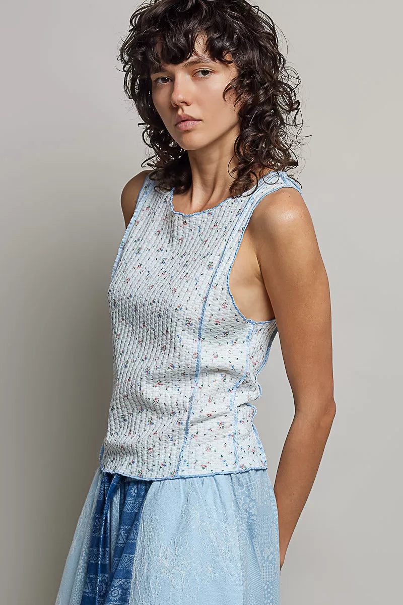 Light blue sleeveless ribbed tank with round neck; micro-floral print, narrow seams