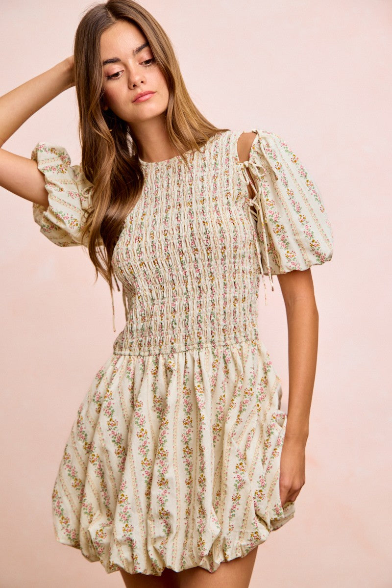Ivory floral mini dress with ruffle hem, smocked center, and bow-tied sleeves