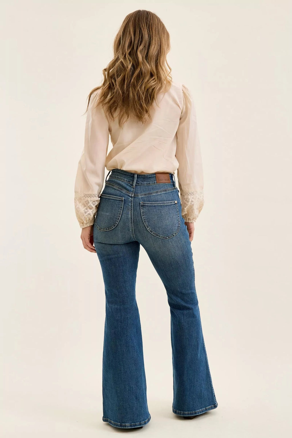 Back view of dark denim high-waist flare jeans with two patch pockets