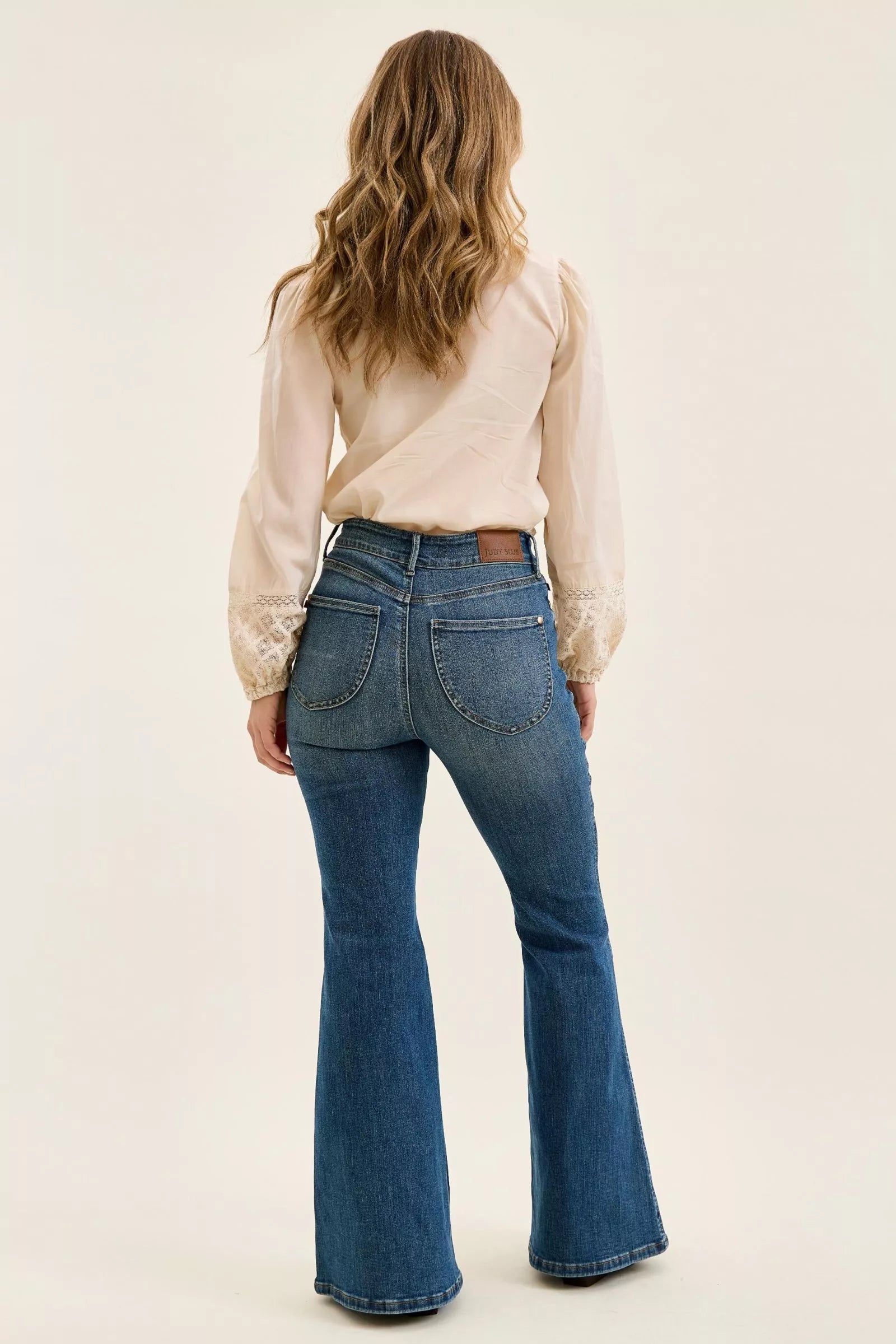 Back view of dark denim high-waist flare jeans with two patch pockets