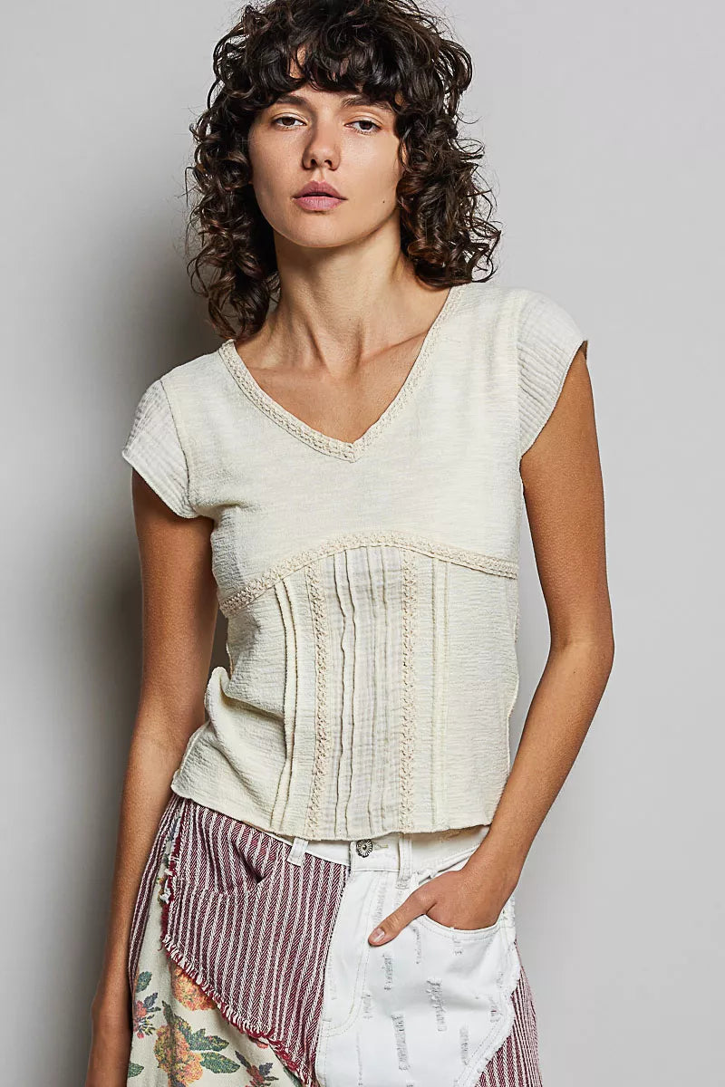Cream textured peplum-style knit top with lace-trimmed V-neck and short sleeves