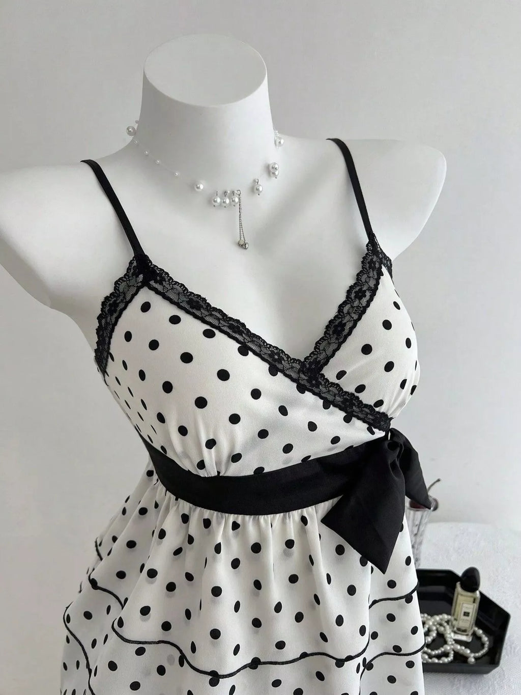 Polka dot camisole with black lace trim, V-neck straps and waist bow