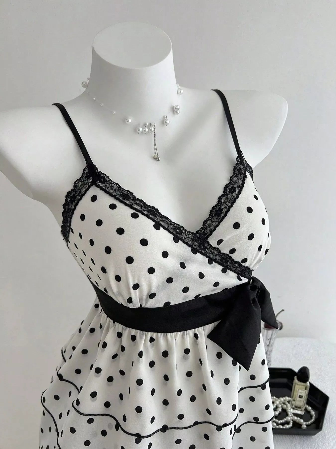 Polka dot camisole with black lace trim, V-neck straps and waist bow