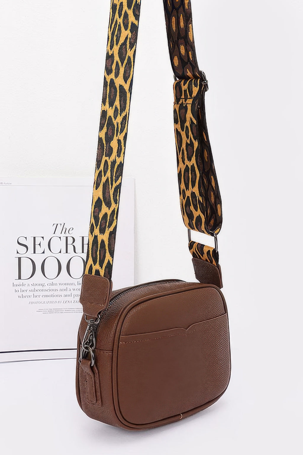 Brown camera bag side view with leopard strap and small chain d-ring