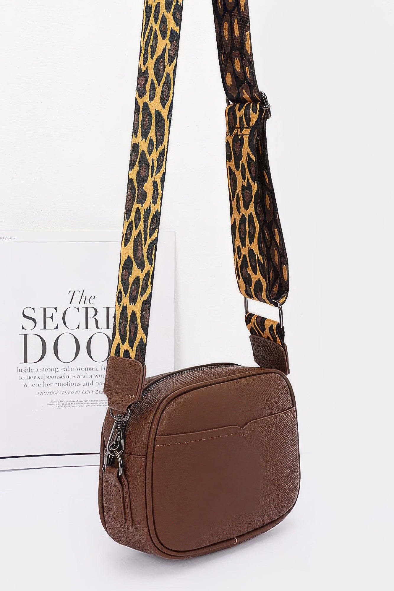 Brown camera bag side view with leopard strap and small chain d-ring