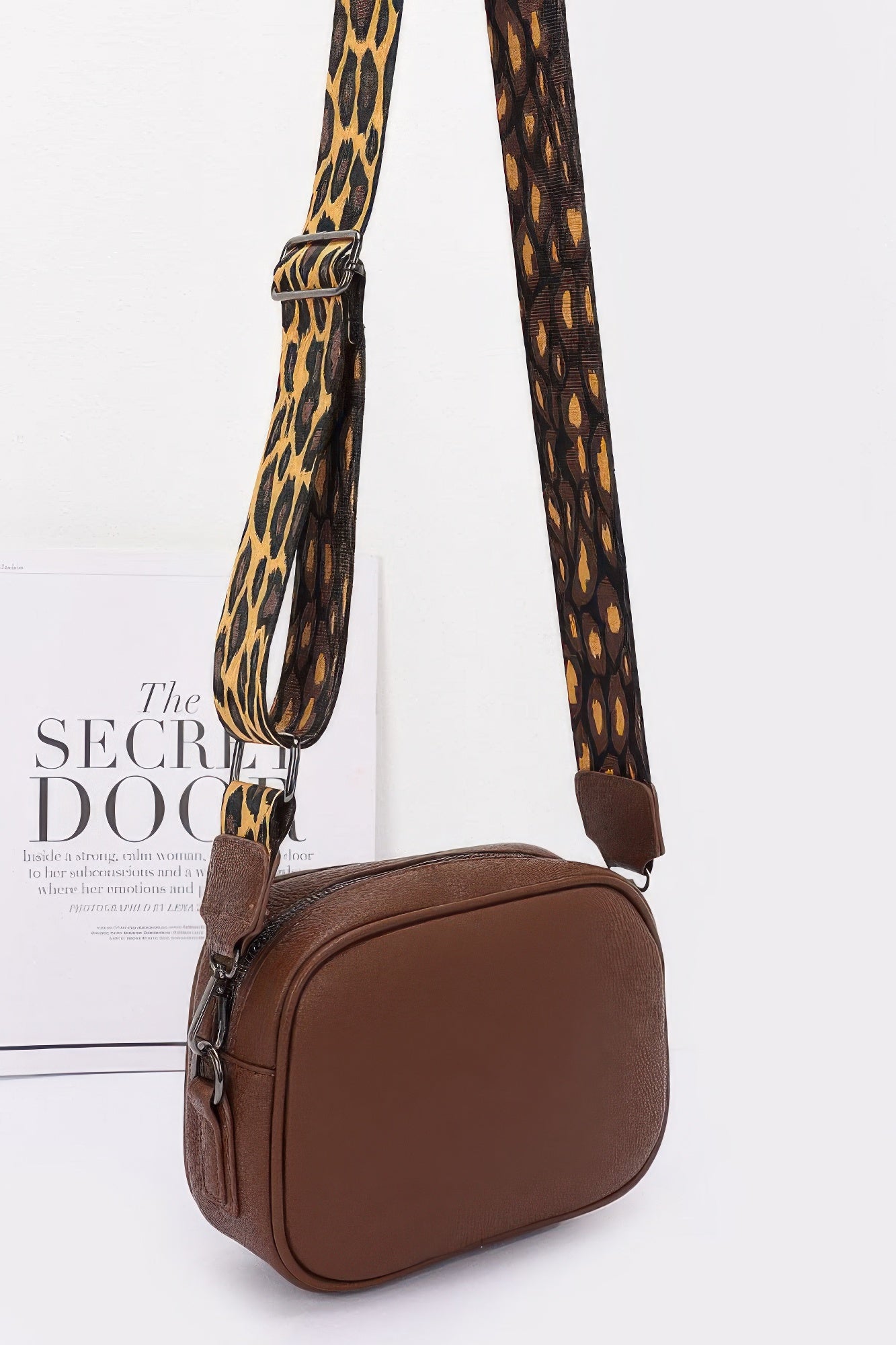 Brown faux leather camera bag with leopard strap, angled front view