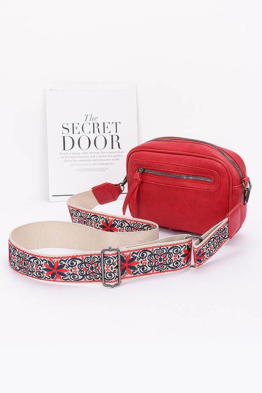 Red faux leather camera bag with front zip pocket and multicolor patterned strap