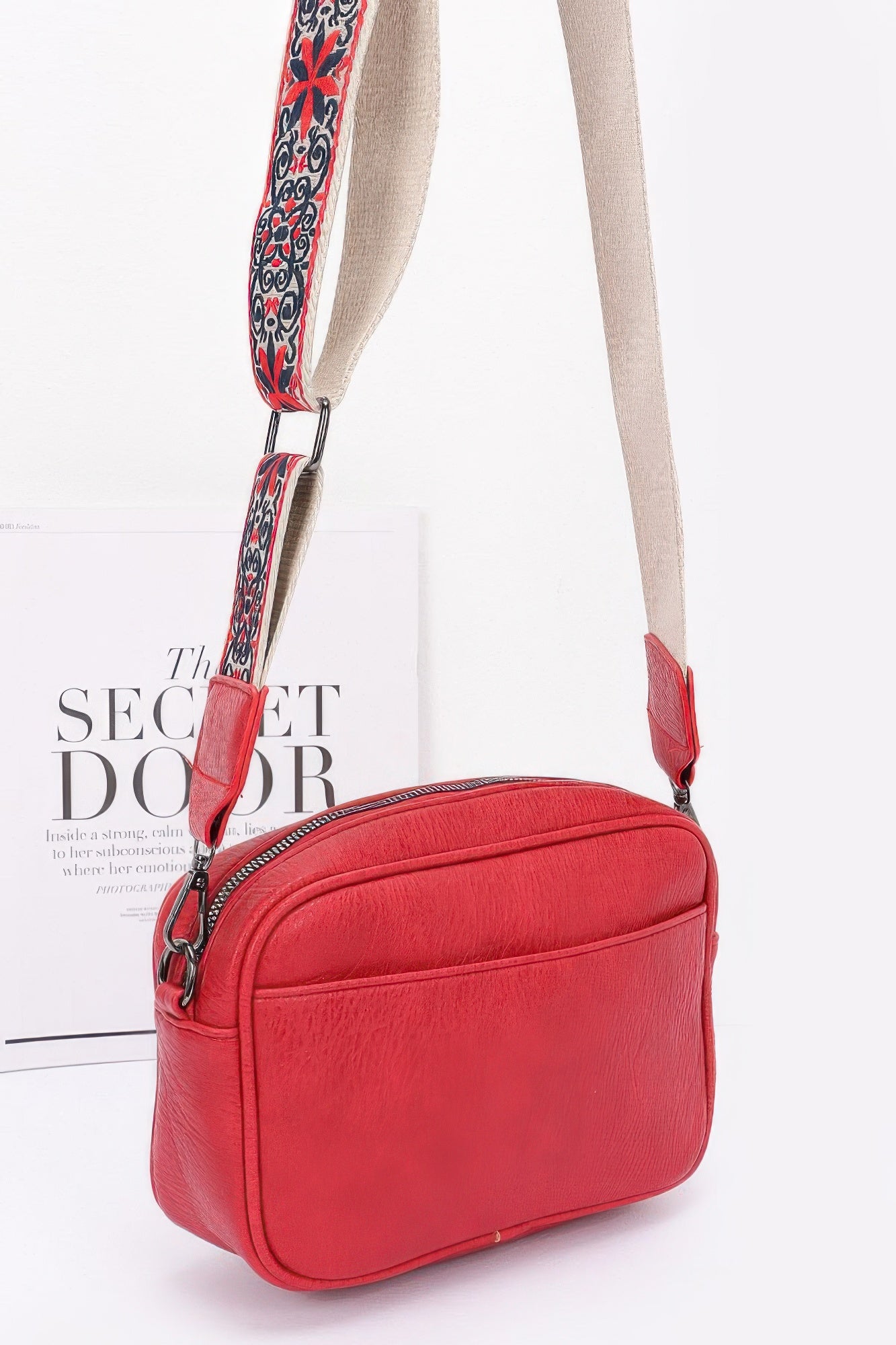 Red faux leather camera bag with adjustable patterned strap, side view and zip