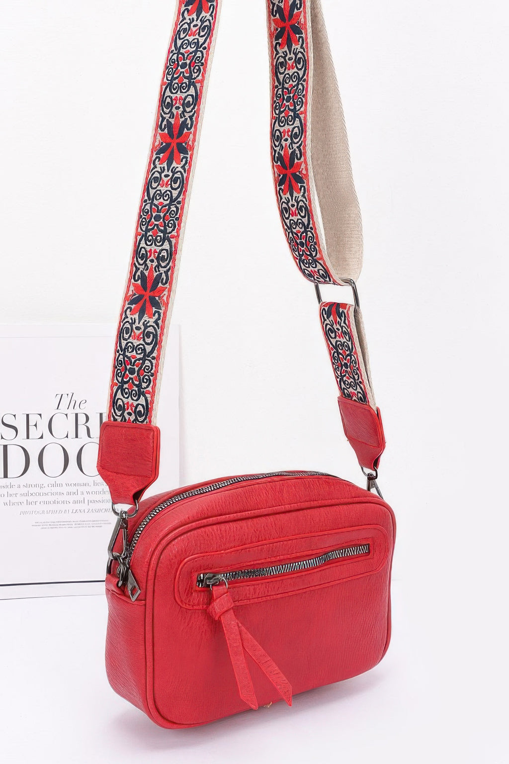 Red faux leather crossbody camera bag with patterned strap and front zipper