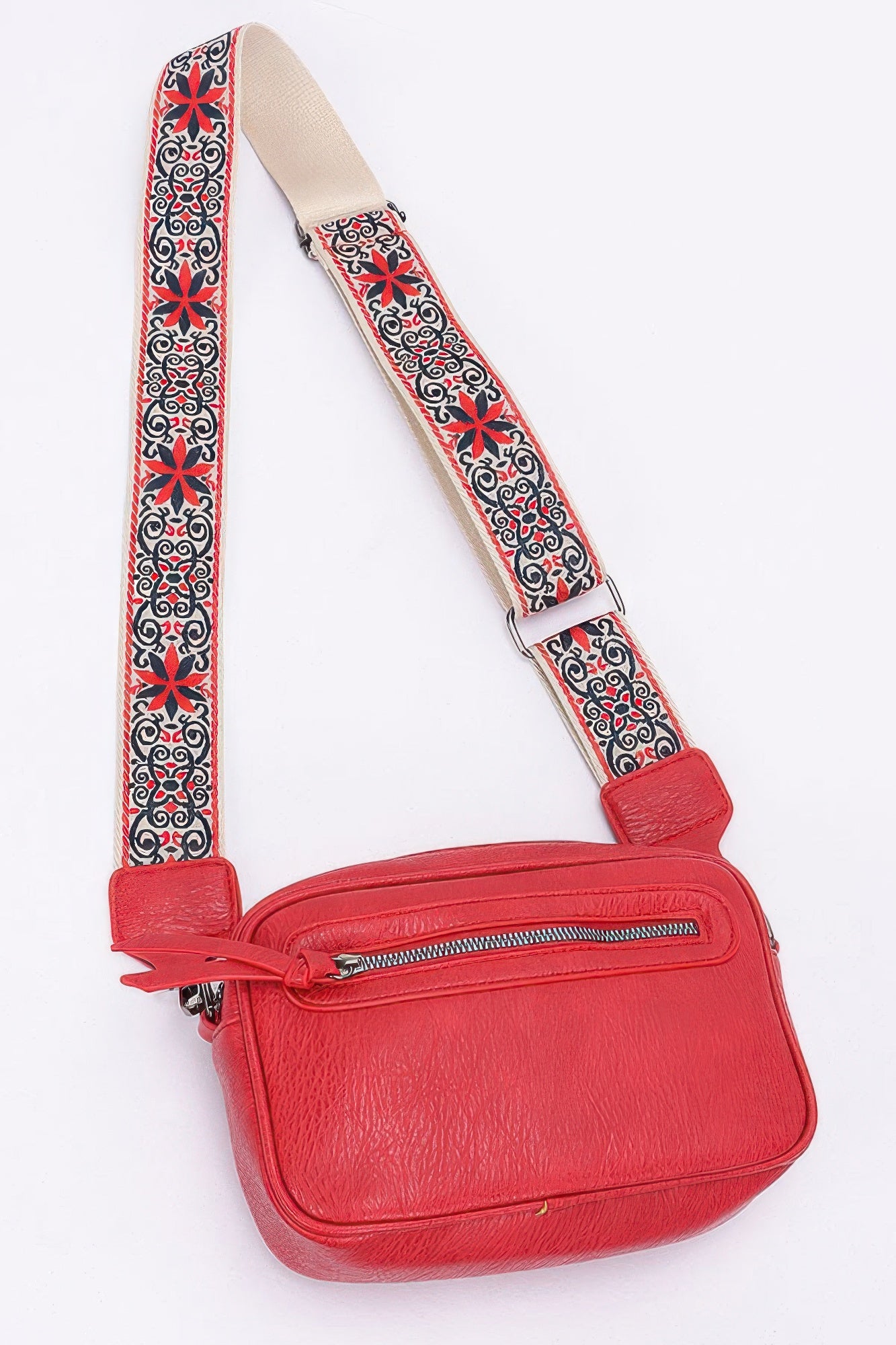 Red faux leather camera bag with front zipper and patterned strap with buckle