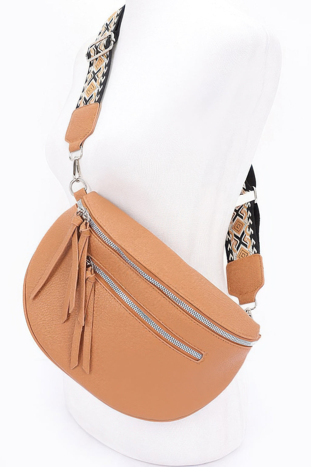 Tan crossbody bag on mannequin, front zip pocket and long tassel ties at the bottom.
