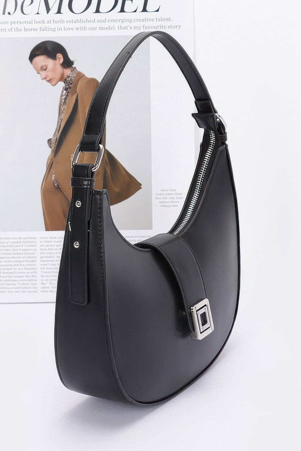 Black faux leather hobo bag, curved silhouette, front buckle detail