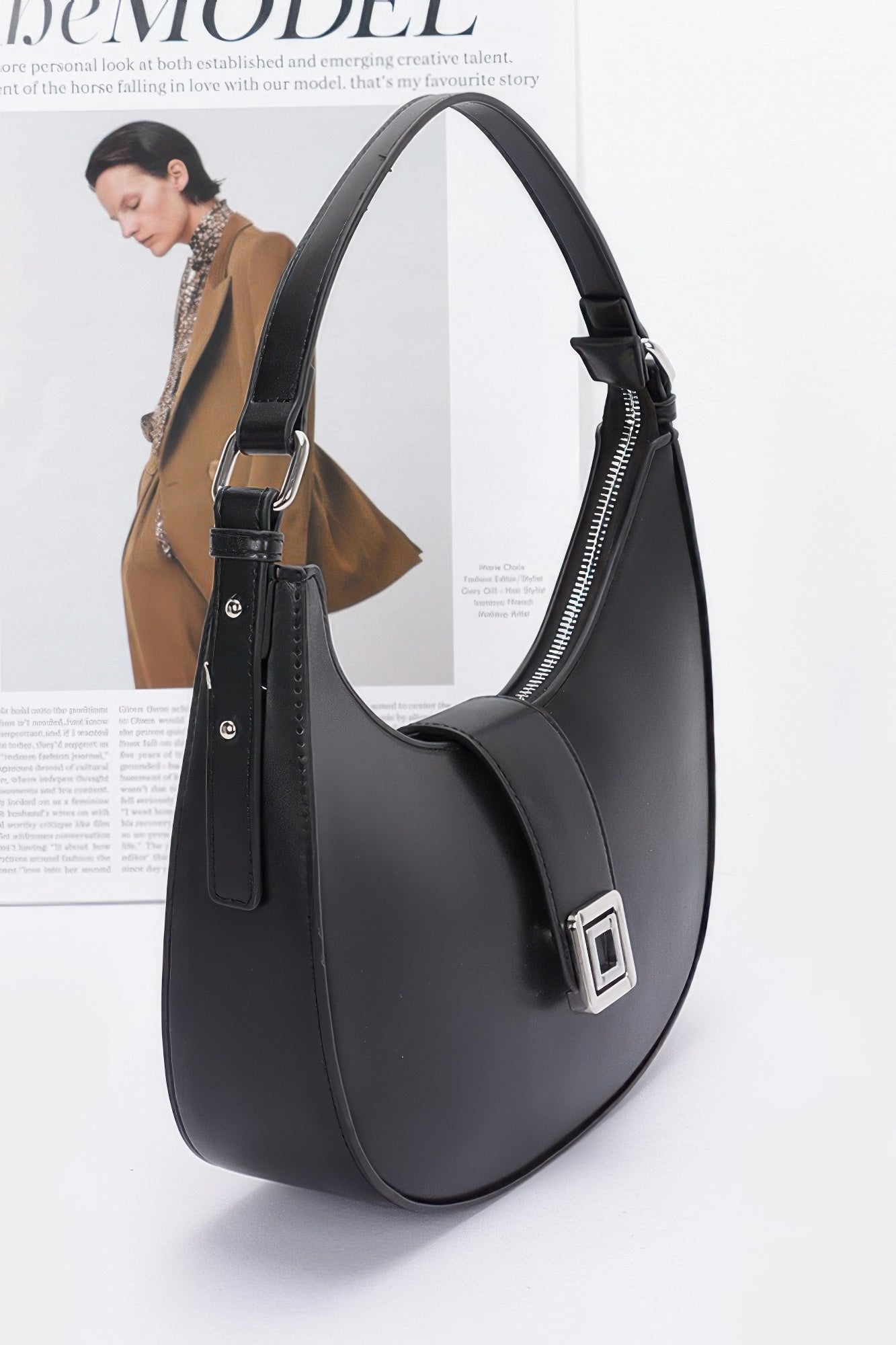 Black faux leather hobo bag, curved silhouette, front buckle detail