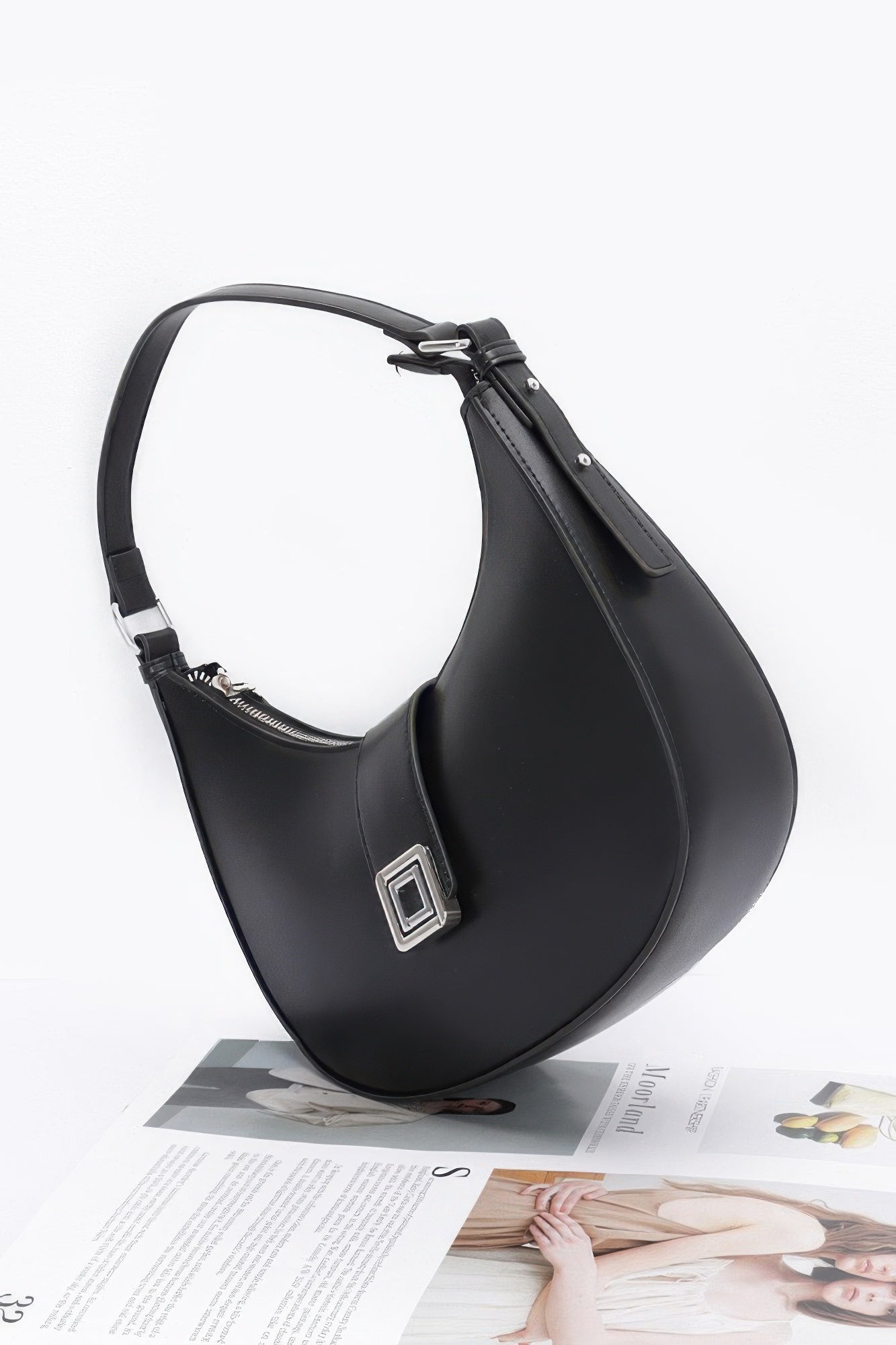 Black faux leather hobo bag side view with top handle and buckle