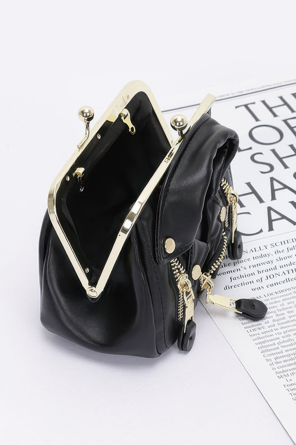 Black faux leather crossbody bag with gold-tone clasp and front zip pockets