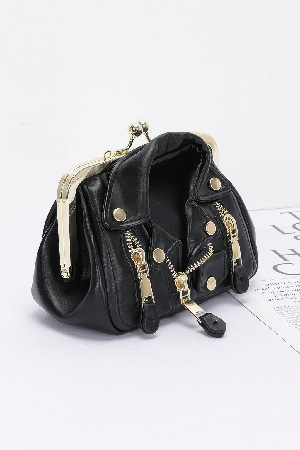 Black faux leather crossbody bag with gold-tone hardware, snap buttons and chain